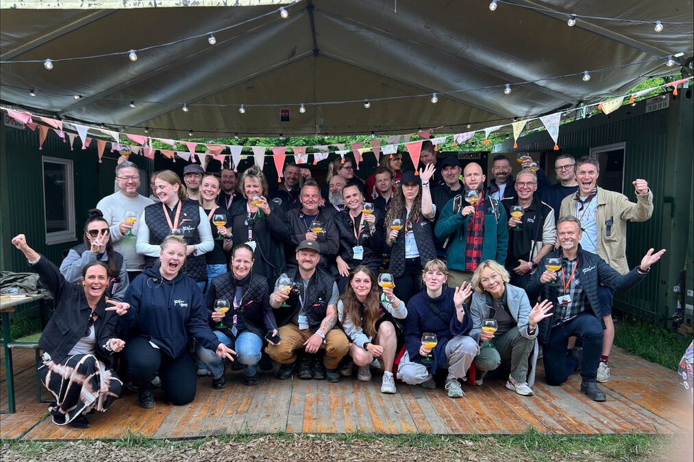 Glad gruppe frivillige hos Jelling Musikfestival fejrer en arbejdsdag under lyskæder